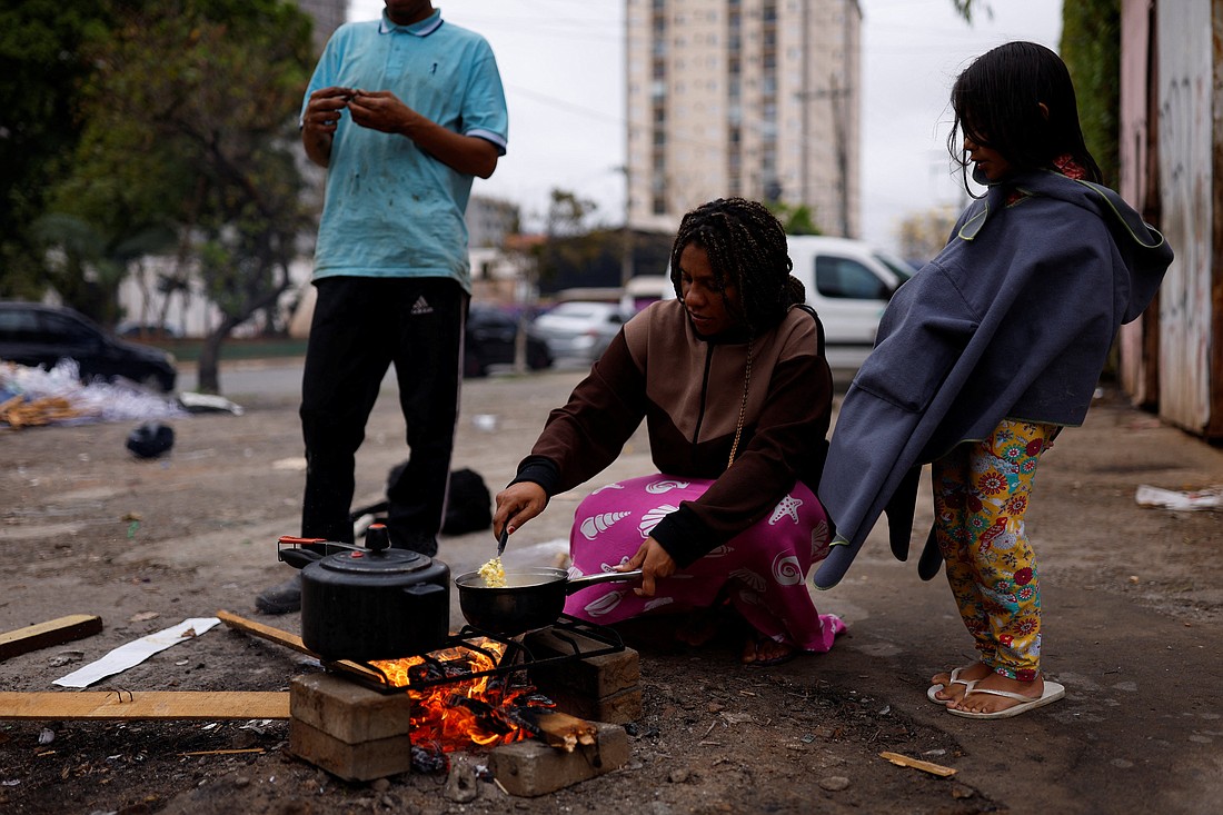 Carla Marquez, 36, who is six months pregnant, burns wood on the street to cook a meal for her husband, Carlos Henrique Mendes, 25, and their daughter, Gabriela, 5, outside their home in São Paulo Sept. 16, 2022. Marquez and her family live in a room paid for by a church and struggle to feed their daughter. Among the challenges identified during the process of the Latin American church's First Ecclesial Assembly were social and economic inequalities exacerbated by the pandemic. (CNS photo/Amanda Perobelli, Reuters)