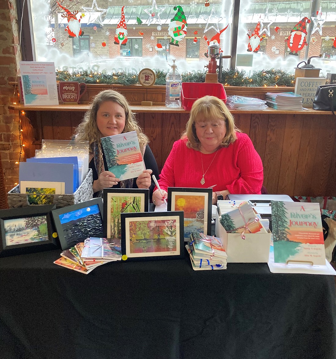 Lisa Cupolo (l.) and her mother, Nancy, are seen at a signing for their book, "A River's Journey" at the Coffee Planet in Ballston Spa last year. The children's book was written by Nancy and illustrated by Lisa. To see one of Lisa’s pieces of art from the book in color, turn to page 20. (Provided photo)