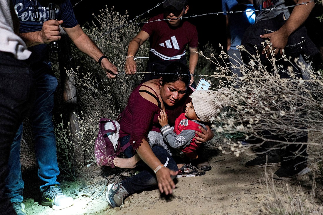 Asylum-seeking migrants' families go under a barbed wire fence while being escorted by a local church group to the location where they turn themselves in to the U.S. Border Patrol, after crossing the Rio Grande river into the United States from Mexico, in Roma, Texas, April 16, 2021.  Catholic and human rights organizations react to July 2023 reports that Texas authorities are employing inhumane tactics against migrants and asylum seekers along the Rio Grande. (OSV News photo/Go Nakamura, Reuters)