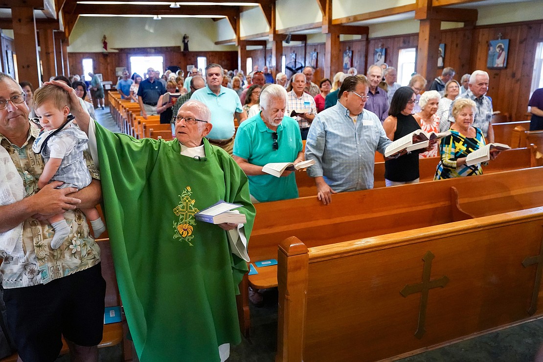 Father Robert Hohenstein lays his hand on Quinn Olson, 9 months, during the procession to the altar on Sunday, July 23, 2023, at St. Isaac Jogues Chapel, which is open from Memorial Day “til the snow flies,” in Saratoga Springs, N.Y.  Cindy Schultz for The Evangelist