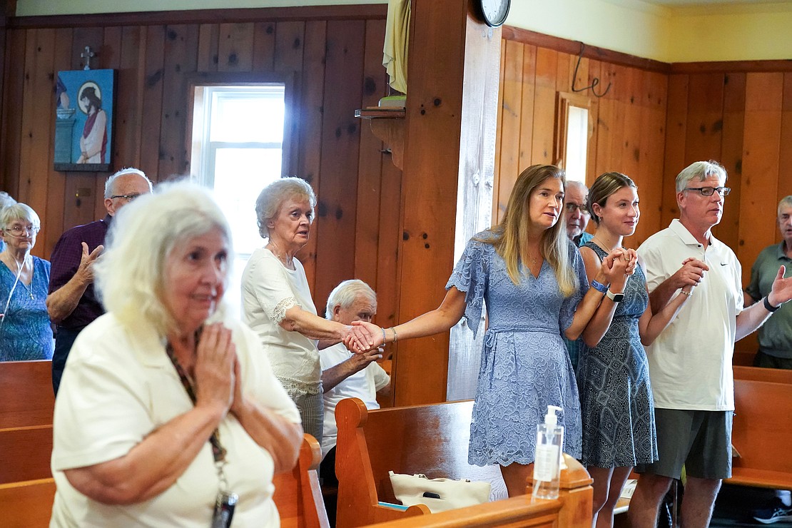 Judi McSwieney, center, joins hands with her mother Carol Urbaetis, left, daughter Gabriela McSwieney and husband John McSwieney during the Lord’s Prayer on Sunday, July 23, 2023, at St. Isaac Jogues Chapel, which is open from Memorial Day “til the snow flies,” in Saratoga Springs, N.Y.  Cindy Schultz for The Evangelist