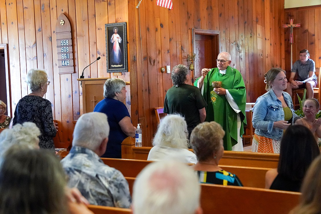 Father Robert Hohenstein gives communion to parishioners during mass on Sunday, July 23, 2023, at St. Isaac Jogues Chapel, which is open from Memorial Day “til the snow flies,” in Saratoga Springs, N.Y.  Cindy Schultz for The Evangelist
