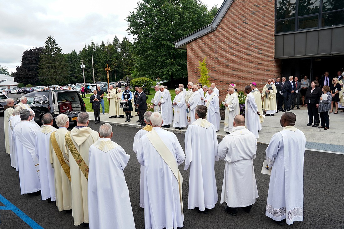 Priests and deacons pay homage to Bishop Emeritus Howard Hubbard after the casket is placed in a hearse following his funeral service on Friday, Aug. 25, 2023, at St. Pius X Church in Loudonville, N.Y.  Cindy Schultz for The Evangelist