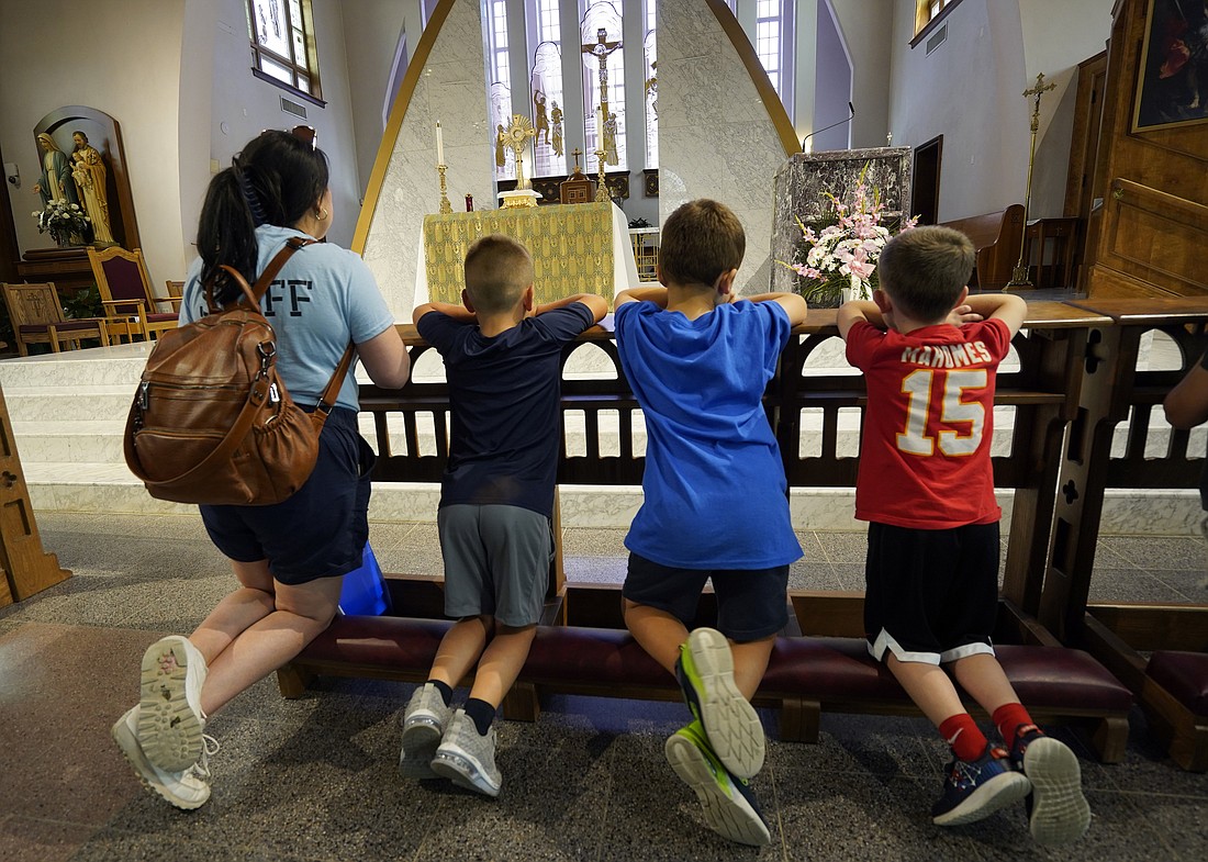 Camp counselor Theresa Vogel and young campers kneel before a monstrance containing the Blessed Sacrament during summer day camp at Notre Dame Church in New Hyde Park, N.Y., July 25, 2023. Each camp day begins with morning Mass and also includes Eucharistic adoration in the afternoon. (OSV News photo/Gregory A. Shemitz)