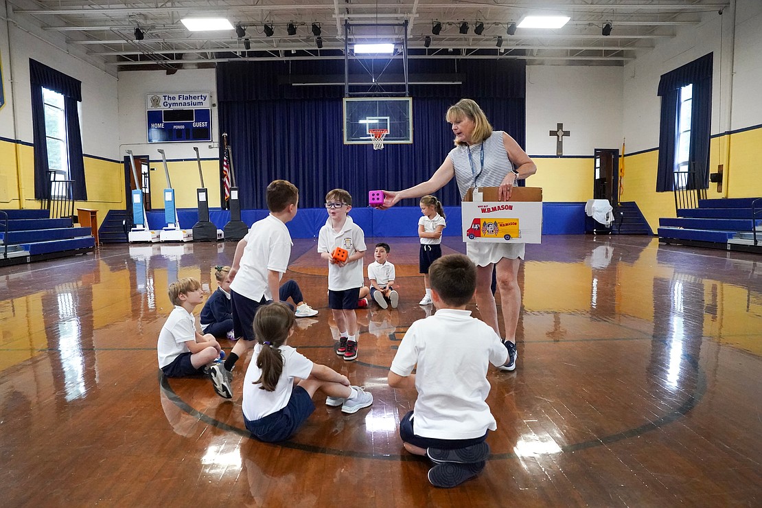 Physical Education teacher Joann Stevens hands out sponge dice for first graders to use for an exercise game on Sept. 12 at St. Clement's School in Saratoga Springs. Cindy Schultz photo for The Evangelist