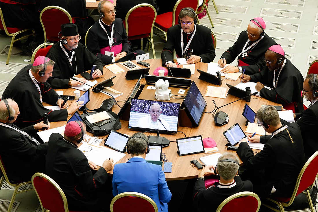 Pope Francis is seen on a monitor as he speaks to participants in the assembly of the Synod of Bishops during their first working session in the Paul VI Audience Hall at the Vatican Oct 4, 2023. (CNS photo/Lola Gomez)