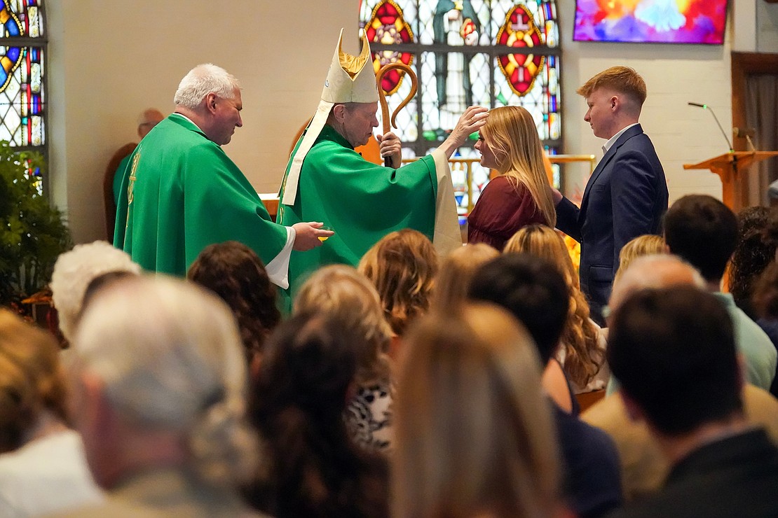 Bishop Edward B. Scharfenberger uses chrism to anoint candidate Emma Moran with sponsor Zachary Moran during confirmation on Oct. 29 at St. Kateri Tekakwitha Parish in Schenectady. At left, Father Bob Longobucco holds the chrism. (Cindy Schultz photo for The Evangelist)