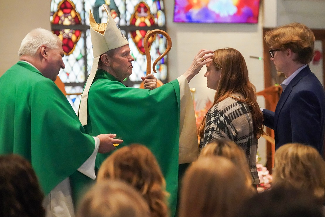 Bishop Edward B. Scharfenberger uses chrism to anoint candidate Avery Watson with sponsor Patrick Connelly during confirmation on Oct. 29 at St. Kateri Tekakwitha Parish in Schenectady. Father Bob Longobucco holds the chrism. (Cindy Schultz photo for The Evangelist)