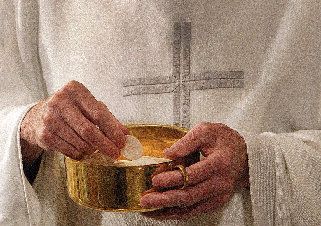 This photo illustration shows a priest preparing to distribute Communion during Mass. A civil suit filed Nov. 16, 2023, alleging a Rochester, N.Y., diocesan priest abused a vulnerable adult shows the Catholic Church in the U.S. has significant work to do in safeguarding adults from clerical abuse under Pope Francis' motu proprio "Vos Estis Lux Mundi," say experts. (OSV News photo/Bob Roller)