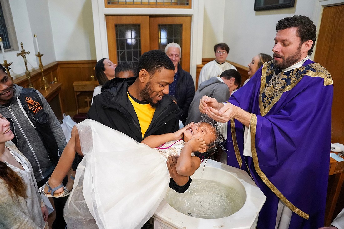 Father Daniel Quinn baptizes Kya’Niyah Harris at the baptismal font on Sunday, Dec. 3, 2023, at Blessed Sacrament in Albany, N.Y. Harris, a first grader at Blessed Sacrament School, was among those who were baptized after Mass. (Cindy Schultz for The Evangelist)