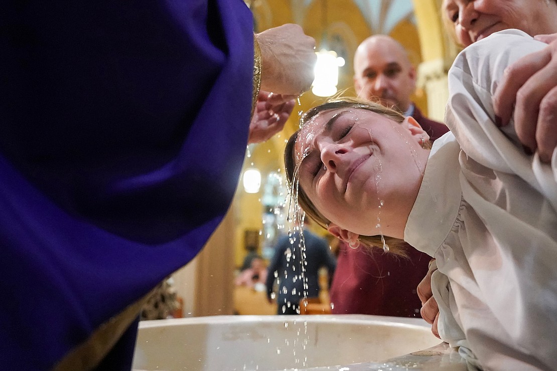 Father Daniel Quinn baptizes Isabella Burgess at the baptismal font on Sunday, Dec. 3, 2023, at Blessed Sacrament in Albany, N.Y. Miss Burgess, a tenth grader at Blessed Sacrament School, was among those who were baptized after mass.  Cindy Schultz for The Evangelist