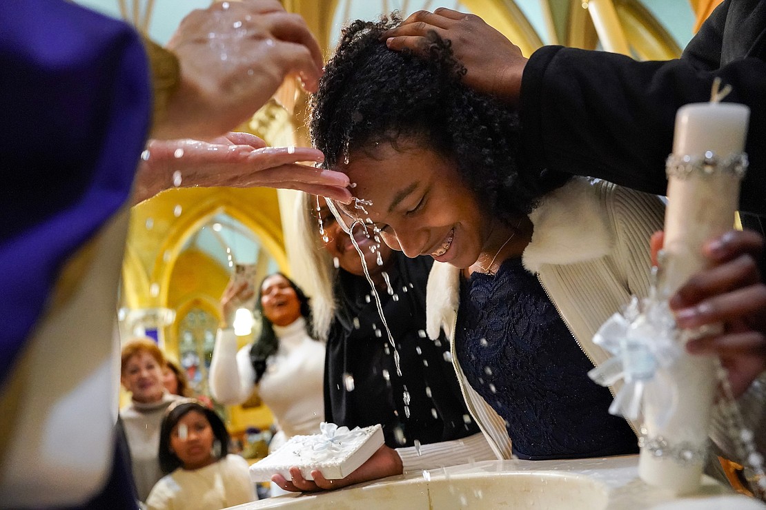 Father Daniel Quinn baptizes Melanie Frias, 15, at the baptismal font on Sunday, Dec. 3, 2023, at Blessed Sacrament in Albany, N.Y.  Cindy Schultz for The Evangelist