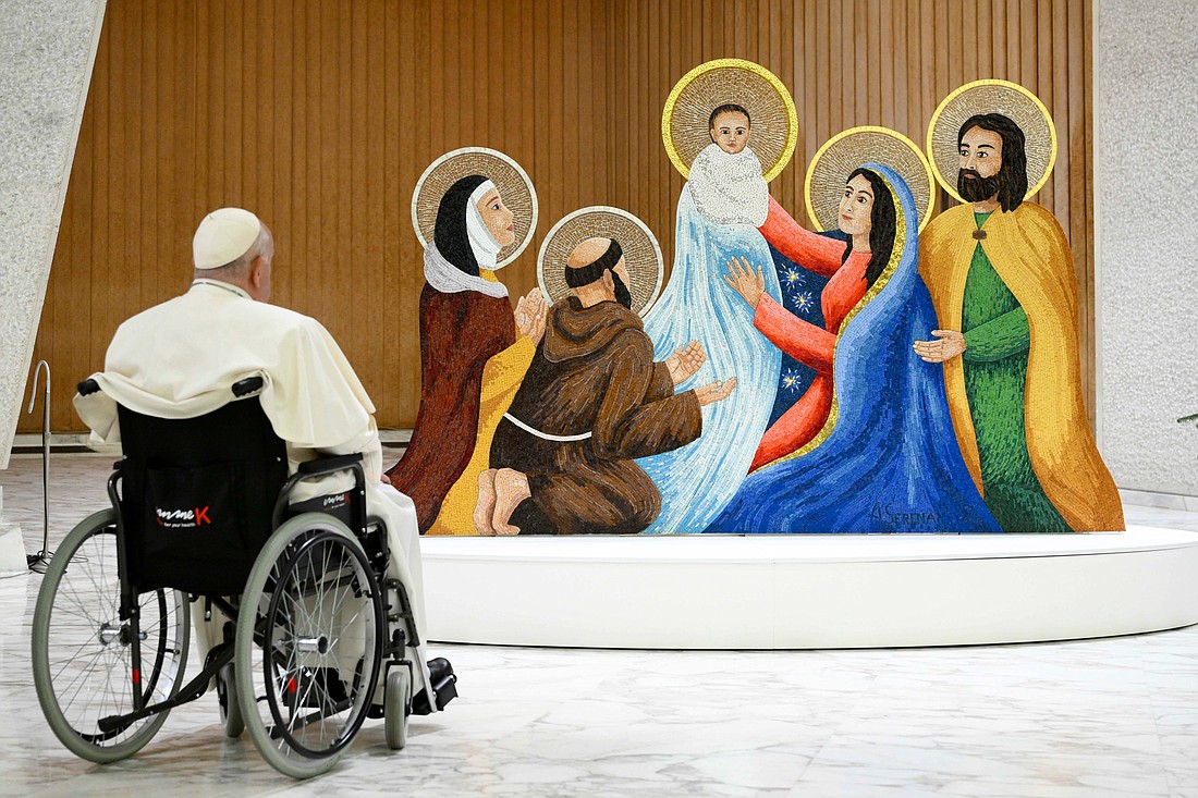 Pope Francis stops to pray in front of a Nativity scene in the Paul VI Audience Hall at the Vatican Dec. 9, 2023, after meeting with donors, artists and local government officials responsible for the Christmas decorations at the Vatican. The scene is a mosaic of Venetian glass tiles created by Alessandro Serena and features St. Francis and St. Clare of Assisi in celebration of the 800th anniversary of St. Francis staging the first Nativity scene. (CNS photo/Vatican Media)