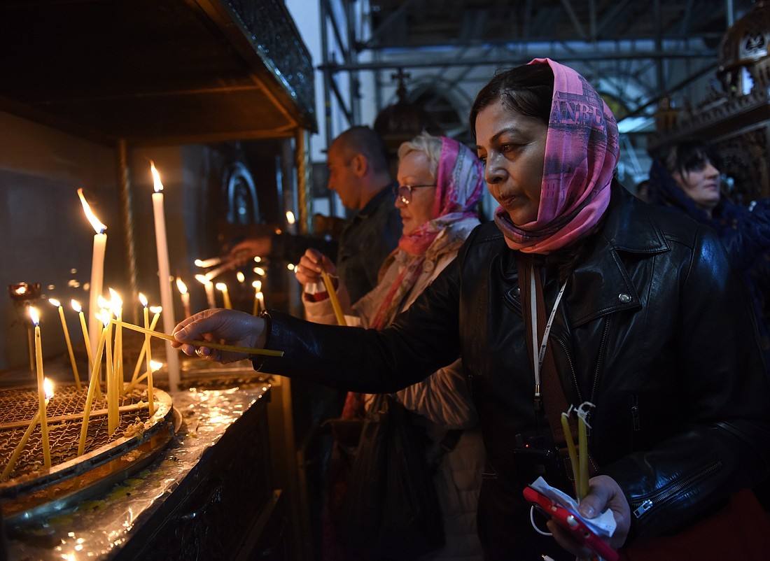 A Christian pilgrim lights a candle in the grotto of the Church of Nativity in Bethlehem, West Bank in this file photo. Amid the ongoing Israel-Gaza war, Christmas in Bethlehem and the Holy Land in 2023 will be one of solemnity, prayer and fasting, the Patriarchs and Heads of the Churches in Jerusalem said. They called upon the faithful to forgo any "unnecessarily festive activities" and to "stand strong" with those facing the afflictions of war, focusing more on the spiritual meaning of Christmas. (OSV News photo/Debbie Hill)