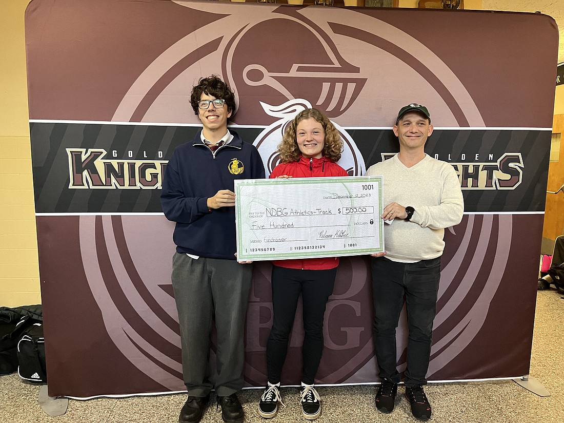 Isaiah Batista, (left), Rebecca Kleiber, and Notre Dame-Bishop Gibbon's track coach, Ken Kienzle, pose for a photo on December 12. Kleiber presented coach Kienzle with a check for $500 as part of her service project for the National Honor Society. The funds will go to new equipment for the NDBG track team. (Emily Benson photo)