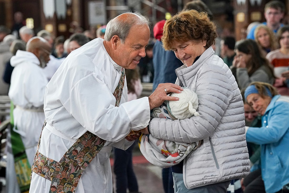 Deacon Norbert Archibald of Worcester, Mass., blesses 3-month-old Nellie McCoy, who rests in the arms of her grandmother, Karen Riley of Amsterdam, during the New York State Eucharistic Congress on Oct. 22 at Our Lady of Martyrs Shrine in Auriesville. That photo of Nellie inspired her grandmother to write about her experiences at the congress. (Cindy Schultz photo for The Evangelist)