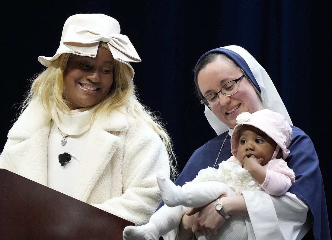 Raisa, a mother who shared her testimony at Life Fest, smiles at one of her daughters in the arms of a member of the Sisters of Life during Life Fest at the D.C. Armory in Washington Jan. 19, 2024, ahead of the annual March for Life. Raisa was pursuing a music career when she learned she was pregnant with twins and turned to the Sisters of Life for help. She also performed a song she wrote called "Madre" at Life Fest. The event was organized and co-sponsored by the Knights of Columbus and Sisters of Life. (OSV News photo/Paul Haring, Knights of Columbus)..