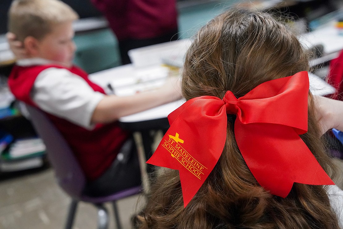St. Madeleine Sophie School fourth-grader Georgette Galarneau-Braungard wears a big red bow with her school’s name on it. (Cindy Schultz photo for The Evangelist)