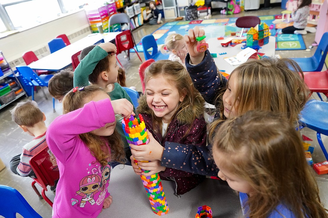 Isabelle Rice (c.) holds onto a colorful tower made of interlocking plastic tiles as her classmates add to it in their Pre-K class at St. Madeleine Sophie School.  (Cindy Schultz photo for The Evangelist)
