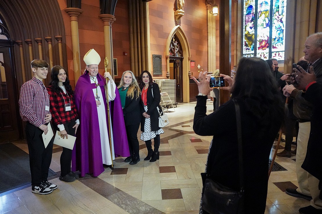 Bishop Edward B. Scharfenberger poses for pictures with newly elects from St. Paul the Apostle Church in Schenectady after the Rite of Election on Feb. 18 at the Cathedral of the Immaculate Conception in Albany. (Cindy Schultz photo for The Evangelist)