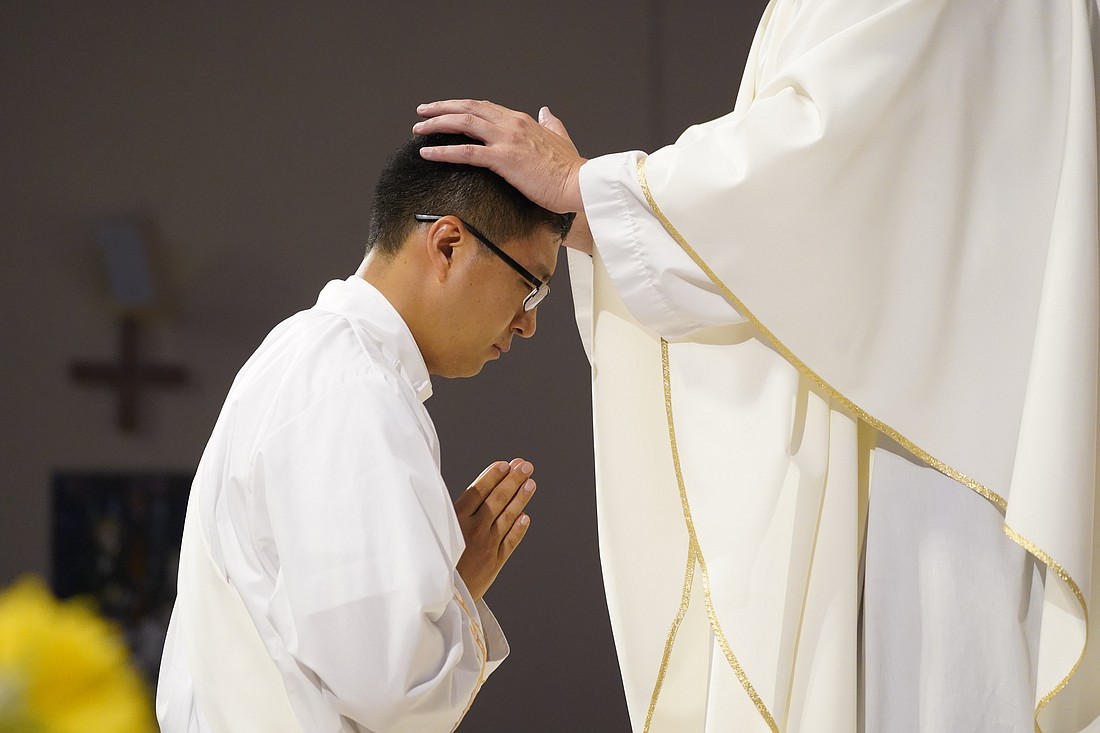 Father Jinwoo (Michael) Nam, a member of the Idente Missionaries, kneels in the sanctuary as a priest lays hands on him during his ordination to the priesthood at St. Agnes Cathedral in Rockville Centre, N.Y., June 10, 2023. Personal encouragement and Eucharistic adoration are crucial in fostering vocations to the priesthood, according to data from a report released April 15 by Georgetown University's Center for Applied Research in the Apostolate. (OSV News photo/Gregory A. Shemitz)
