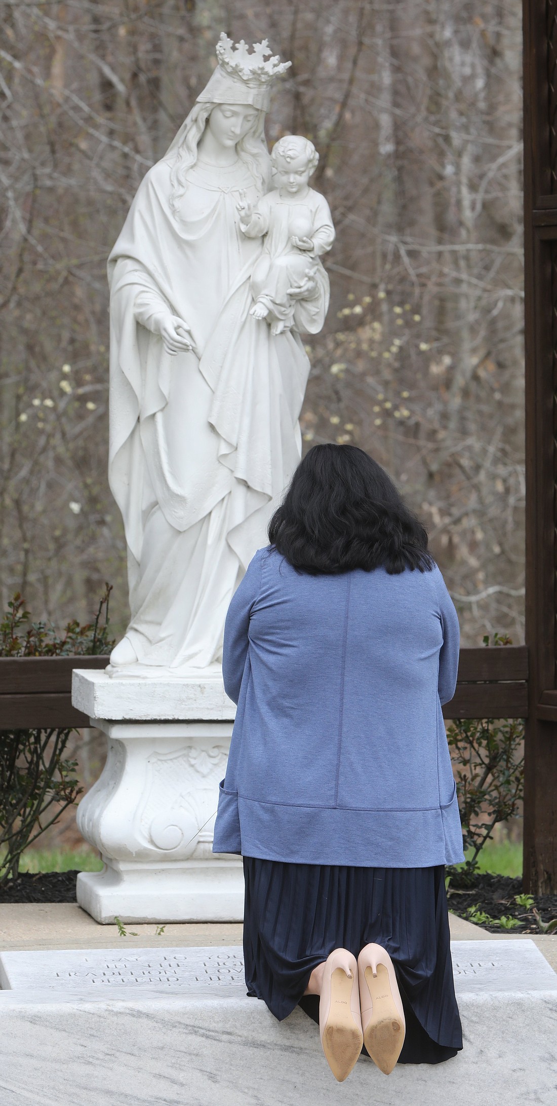 A woman prays before a statue of Mary and the Christ Child before Palm Sunday Mass at Jesus the Divine Word Church in Huntington, Md., April 10, 2022. (OSV News photo/Bob Roller)