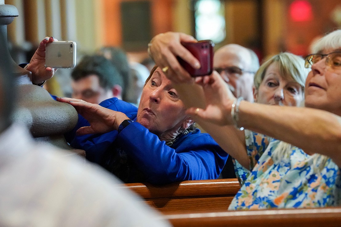Susan DePaula, center, family friend of Father Paul McDonald, looks around a column as she tries to capture the moment during the Ordination of Priests on Saturday, May 18, 2024, at The Cathedral of the Immaculate Conception in Albany, N.Y.  Cindy Schultz for The Evangelist