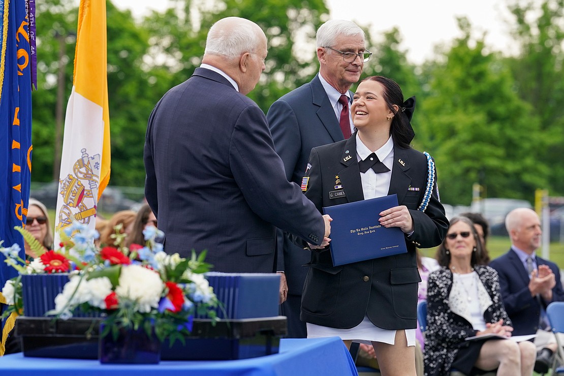 Graduate Grace Camenga receives her diploma from out-going president Joseph Raczkowski, left, and commencement speaker Donald Reutemann during commencement exercises on Saturday May 18, 2024, at La Salle Institute in Troy, N.Y.  Cindy Schultz for The Evangelist