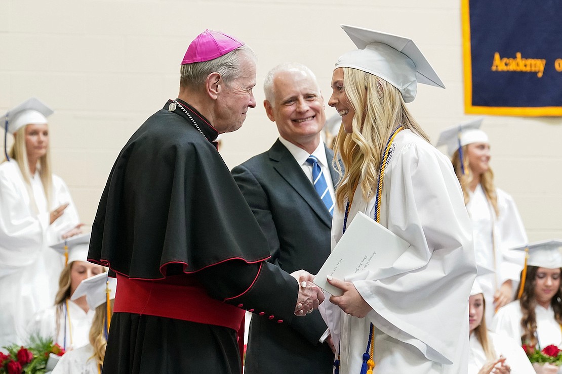 Graduate Abigail LaPlante, right, shakes hands with Bishop Edward B. Scharfenberger, left, as principal Martin Kilbridge looks on during commencement exercises on Friday May 24, 2024, at the Academy of the Holy Names in Albany, N.Y.  Cindy Schultz for The Evangelist