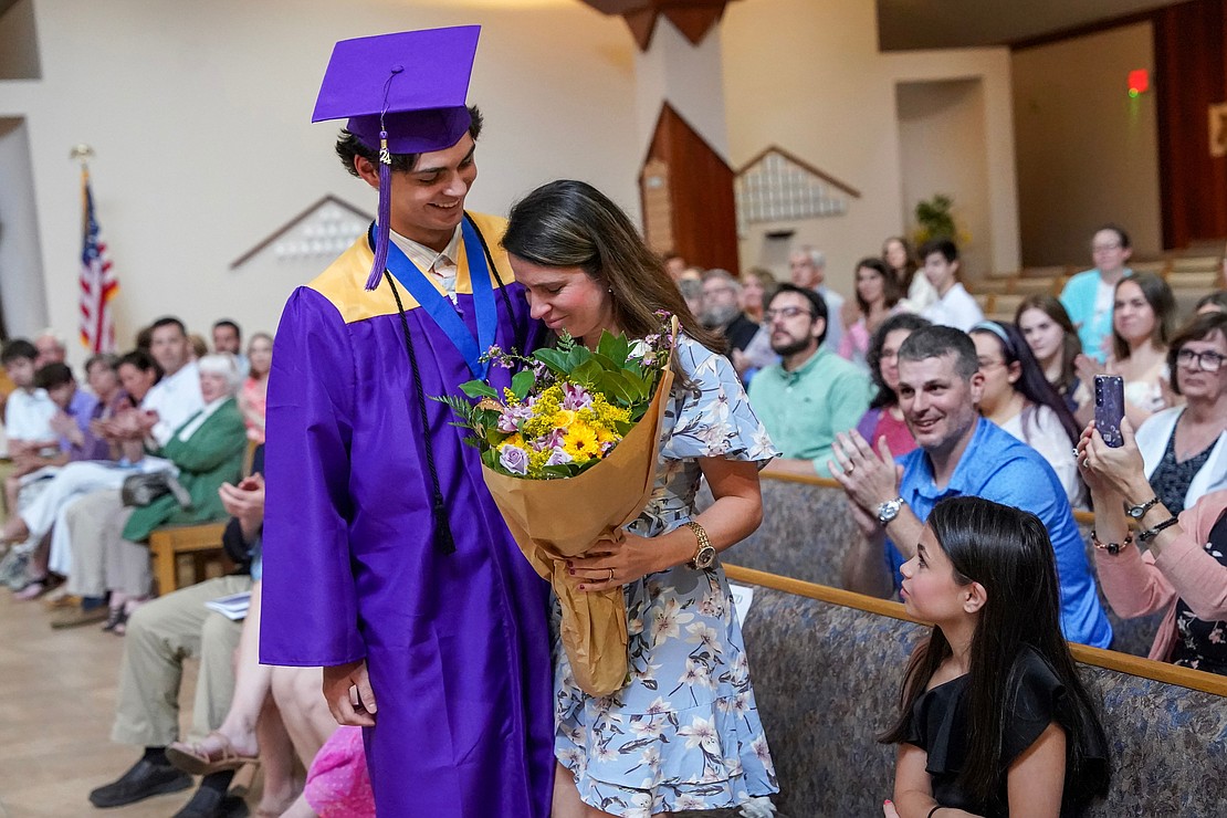 Graduate Aidan Crowther gives flowers to his mother Erin Crowther during commencement exercises for Saratoga Central Catholic School on Friday, June 7, at Corpus Christi Church in Round Lake. (Cindy Schultz photo for The Evangelist)