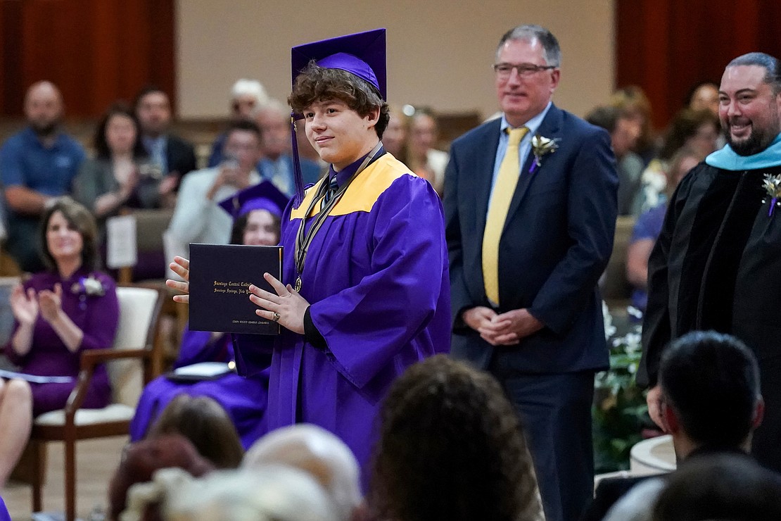 Graduate Joseph Lombardo shows off his diploma for a picture during commencement exercises for Saratoga Central Catholic School on Friday, June 7, at Corpus Christi Church in Round Lake. (Cindy Schultz photo for The Evangelist)