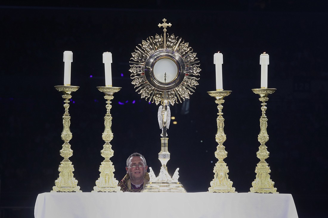 Bishop Andrew H. Cozzens of Crookston, Minn., chairman of the board of the National Eucharistic Congress, Inc., kneels in prayer before the monstrance during Eucharistic adoration at the opening revival night July 17, 2024, of the 10th National Eucharistic Congress at Lucas Oil Stadium in Indianapolis. (OSV News photo/Bob Roller)