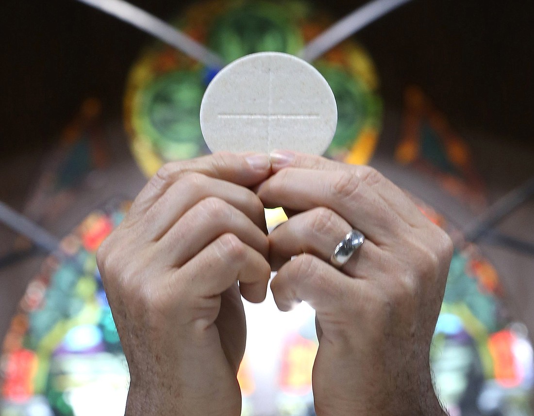 A priest raises the Eucharist in this illustration. (OSV News photo/CNS file, Bob Roller).