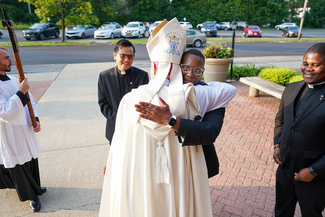 Candidate Franklin Anyanechi, center, embraces Bishop Edward B. Scharfenberger following the Rite of Candidacy and the Rite of Sending on Thursday, Aug. 1, 2024, at Holy Trinity Church in Cohoes, N.Y. Joining them are seminarian Vantuan Cao, left, and candidate Samuel Zuze, right.  Cindy Schultz for The Evangelist