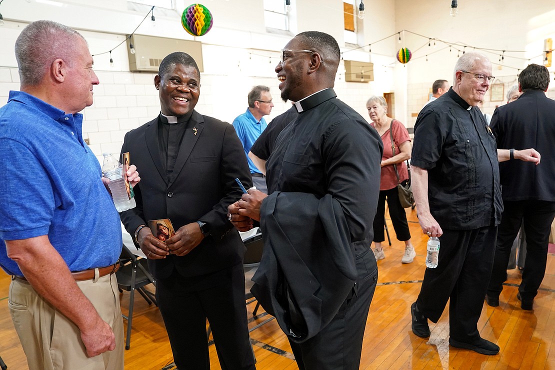 Candidates Samuel Zuze (second from l.) and Franklin Anyanechi talk with parishioner Stephen Crouchley at a reception following the Rite of Candidacy and the Rite of Sending on Aug. 1 at Holy Trinity Church in Cohoes. (Cindy Schultz photo for The Evangelist)