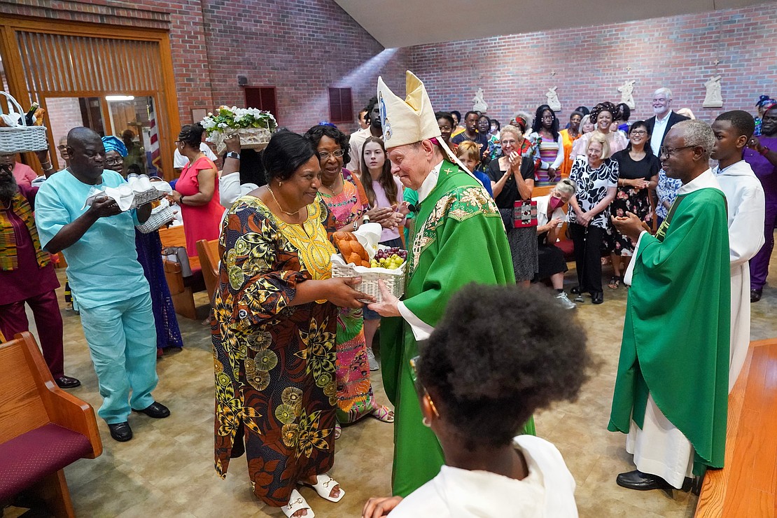 Joelle Mukendi, center left, hands a basket of gifts to Bishop Edward B. Scharfenberger during mass to celebrate the 40th anniversary of the Black Catholic Apostolate on Sunday, Aug.11, 2024, at St. Joan of Arc in Menands, N.Y.  Cindy Schultz for The Evangelist