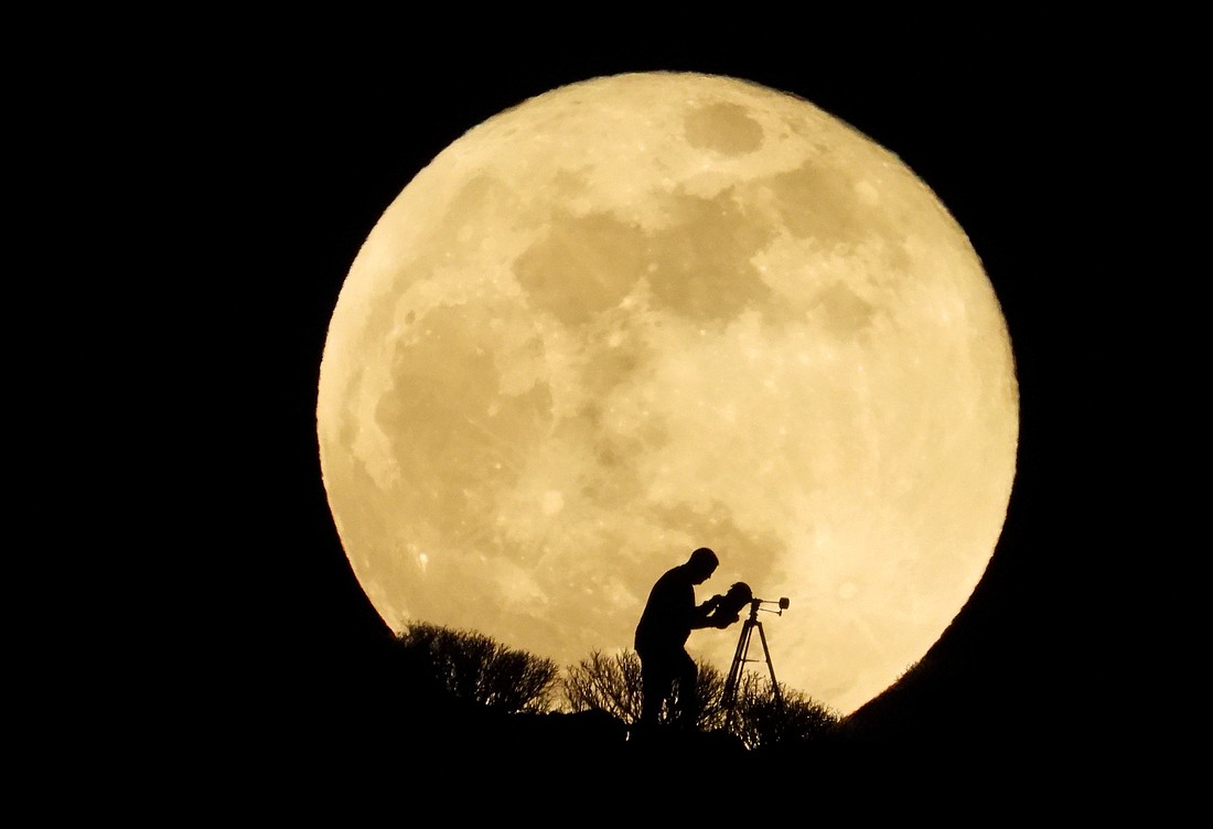 A man uses a telescope to observe the full moon, known as the "Super Flower Moon," as it rises over Arguineguín, Spain in this file photo. (OSV News photo/Borja Suarez, Reuters)