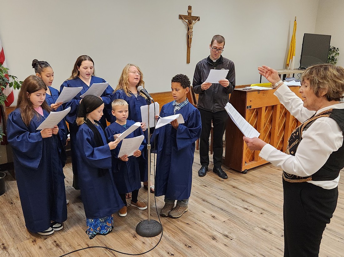 Michela Riccio conducts practice for the children’s choir inside the church hall at St. Mary’s in Amsterdam, as Father Nate Resila, pastor, joins in for a song. The children include: Valentina (from far l., back row), Cardenas, Arianna, Allison, Zephaniah and Fiona (front row) and Harrison. (Provided photo)