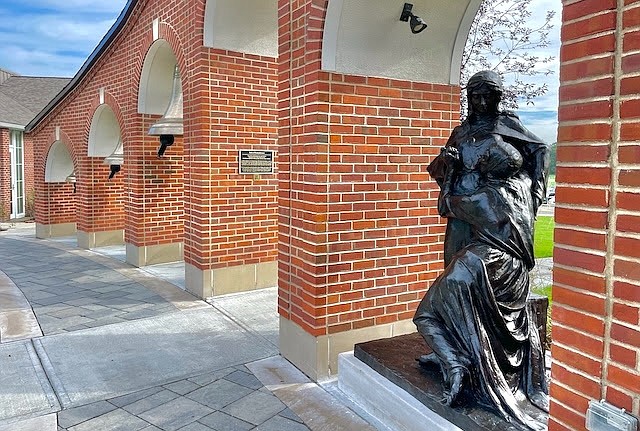 The new statue of St. Clare of Assisi stands in an archway next to the Bells of Remembrance in the Grotto at Siena College. (Photo provided)