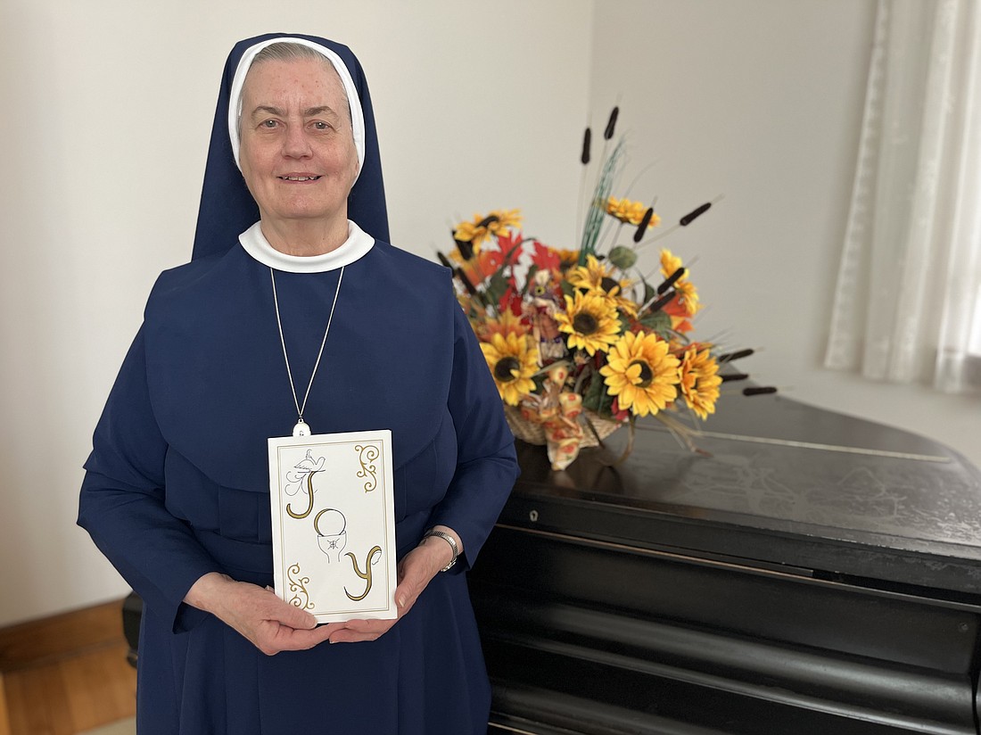 Sister Miriam Ann Thompson, PBVM, holds the invitation she designed for her 50th jubilee celebration. The theme of the day was "joy," and the invite cover includes nods to the Holy Spirit, Mother Mary, and the Eucharist. (Emily Benson photo)