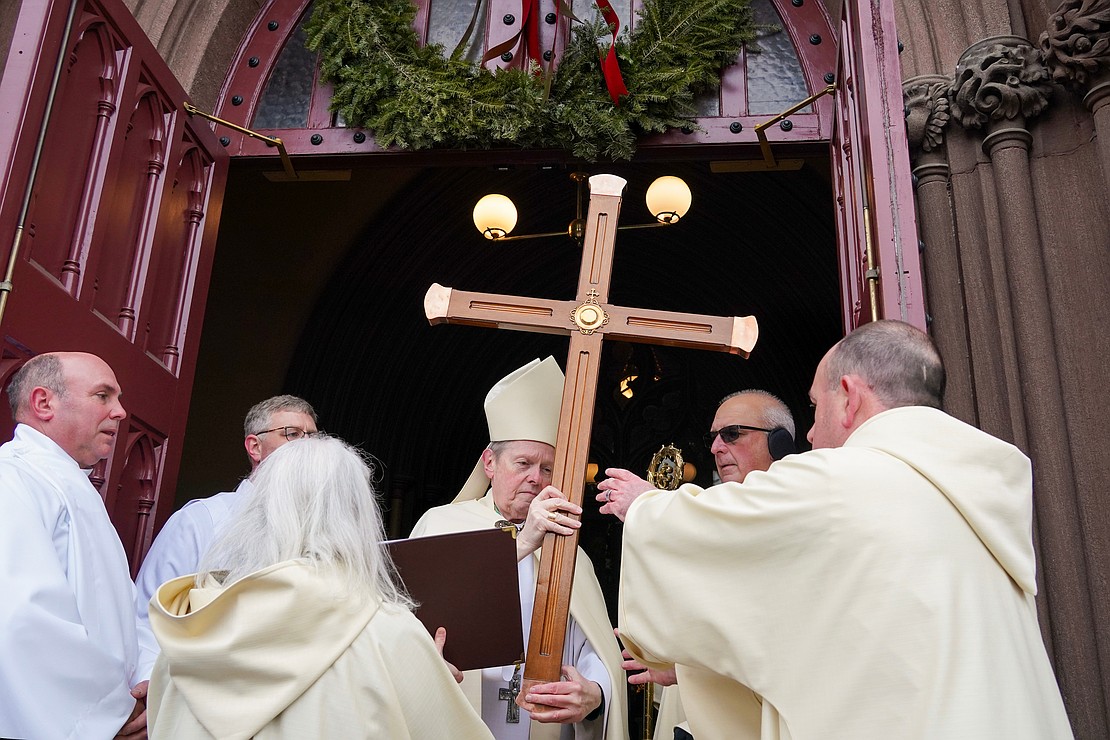 Bishop Edward B. Scharfenberger hands off the Jubilee Cross after blessing the doorway at the Cathedral of the Immaculate Conception on Jan. 5 at the Cathedral of the Immaculate Conception in Albany.(Cindy Schultz for The Evangelist)