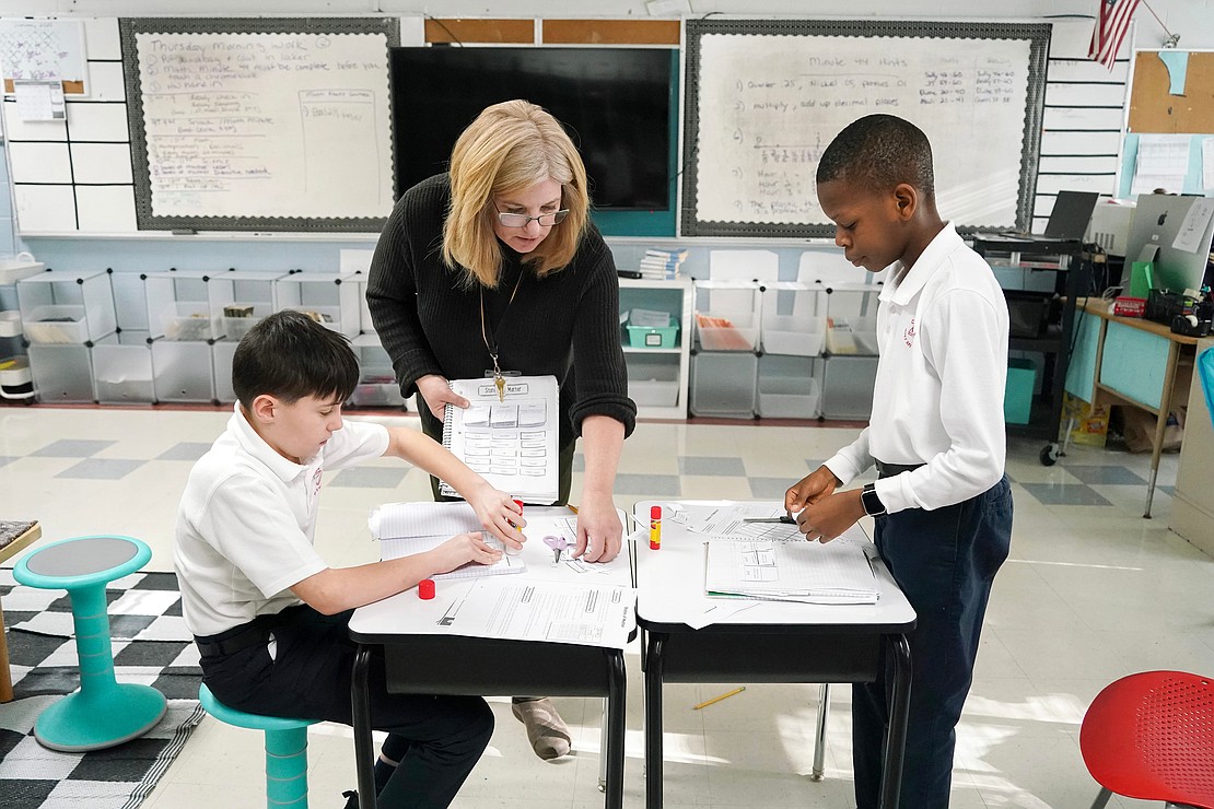 Fifth-grade teacher Robin McDonald, center, helps Brody Fleming, left, and Godson Omoniyi as they study science and states of matter on Jan. 16 at Holy Spirit School in East Greenbush. (Cindy Schultz photo for The Evangelist)