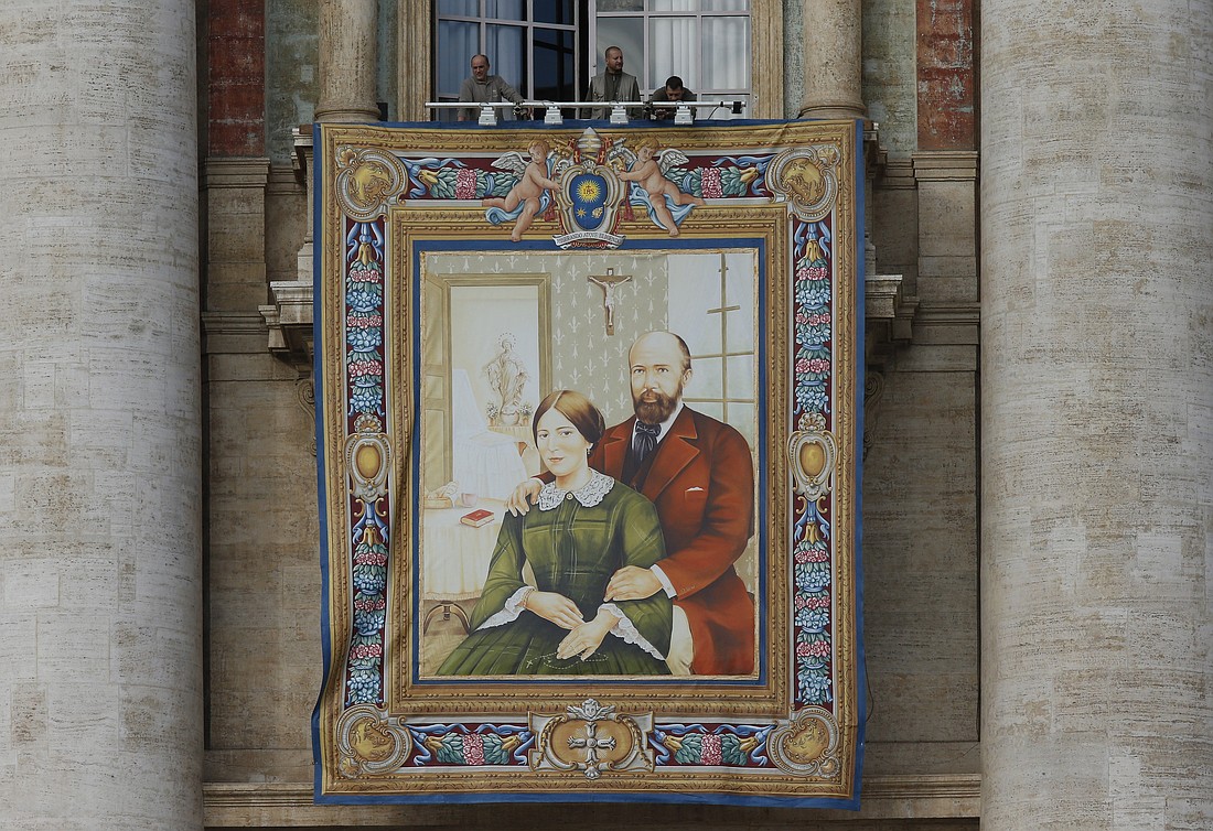 Workers prepare a banner of Louis and Marie Zelie Guerin Martin, the parents of St. Therese of Lisieux, on the facade of St. Peter's Basilica at the Vatican Oct. 16, 2015, in advance of the couple's canonization. (CNS photo/Paul Haring)