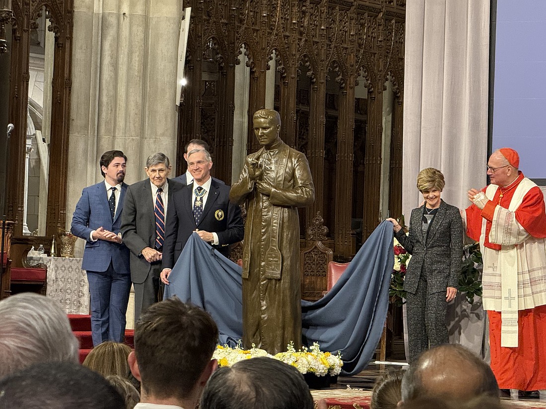 Cardinal Timothy M. Dolan of New York, right, Knights of Columbus Supreme Knight Patrick Kelly, left of statue, and members of the McGivney family unveil a bronze statue of Blessed Michael McGivney donated by the Knights of Columbus to St. Patrick's Cathedral in New York Feb. 22, 2025. (OSV News photo/Steven Schwankert, The Good Newsroom)