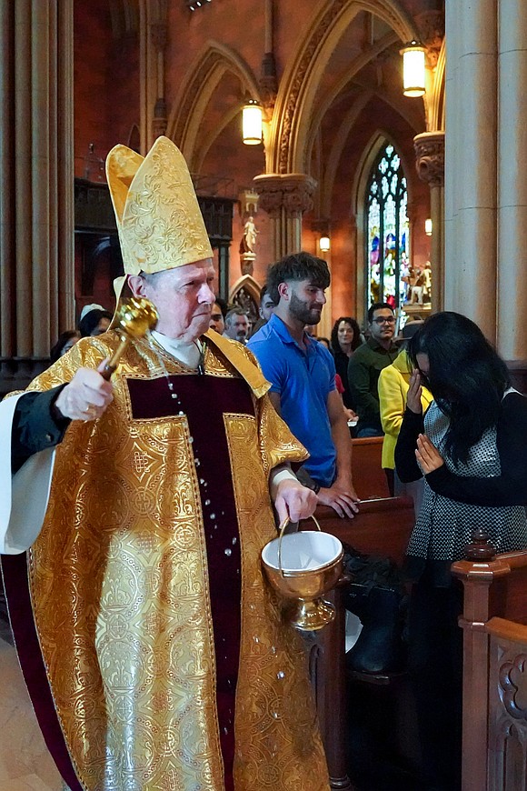 Bishop Edward B. Scharfenberger flicks holy water on the faithful during Easter Mass on April 20 at the Cathedral of the Immaculate Conception in Albany. (Cindy Schultz photo for The Evangelist)