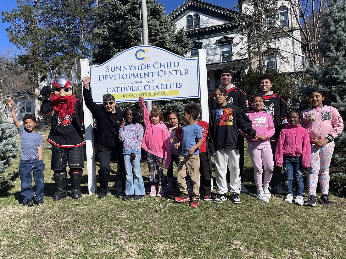 Sister Betsy Van Deusen, CEO of Catholic Charities of the Diocese of Albany, (third from l.), Adirondack Thunder hockey players and their mascot, Gunnar, and after-school program children and staff members, raised a ceremonial flag to kick off the Sunnyside Child Development Center’s 100th anniversary celebration last month. (Photo provided)