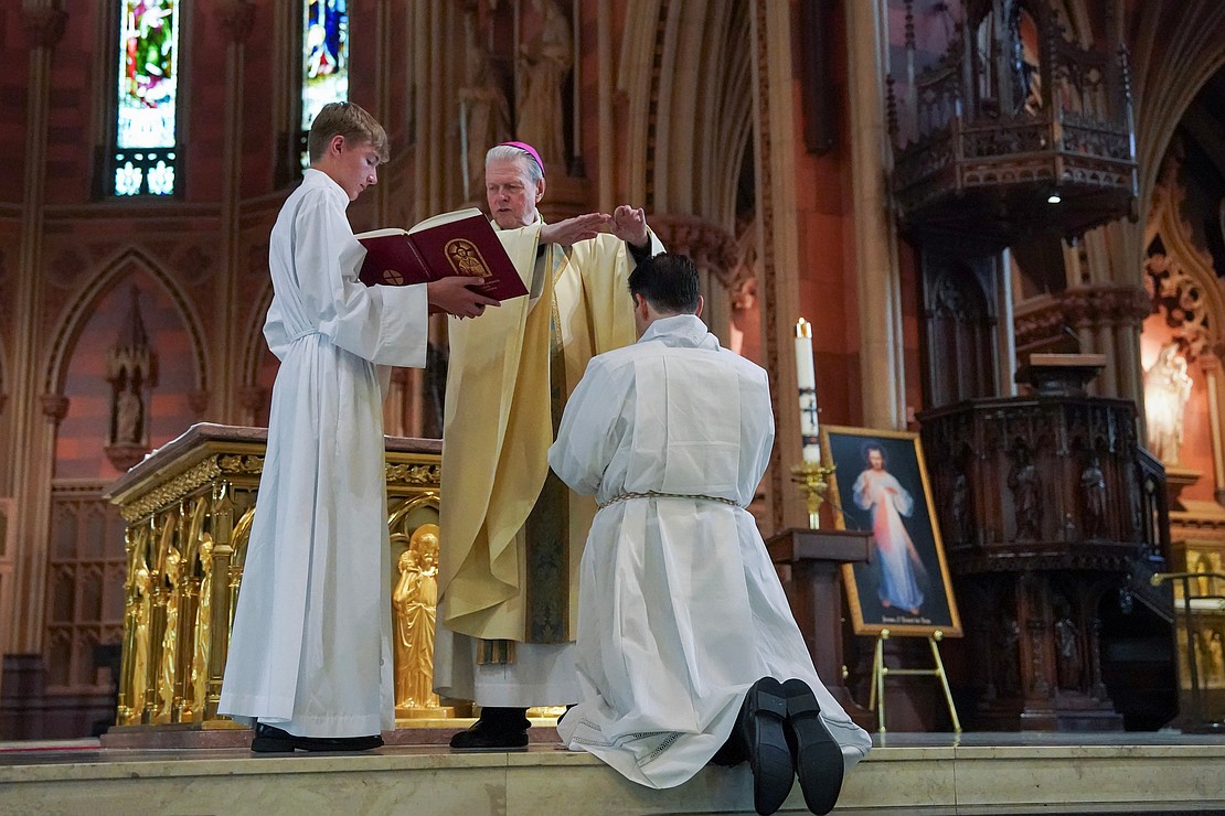 Bishop Edward B. Scharfenberger reads the prayer of ordination to Alexander Turpin, candidate for deacon, during his Ordination to the Diaconate on May 17 at the Cathedral of the Immaculate Conception in Albany. (Cindy Schultz for The Evangelist)