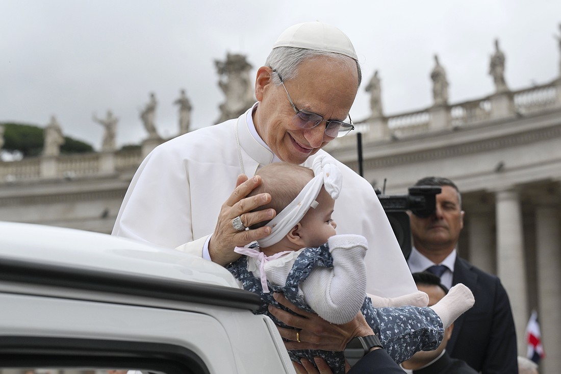 Pope Leo XIV blesses a baby as he rides in the popemobile around St. Peter's Square at the Vatican before his first weekly general audience May 21, 2025. (CNS photo/Vatican Media)