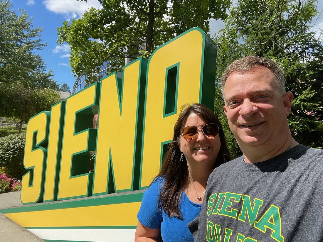 Christopher and Maureen Van Woert stand in front of a sign for their alma mater, Siena College. Both were active participants in the college's Habitat for Humanity program, which Chris helped get recognized as an official chapter for the school. (Provided photo)