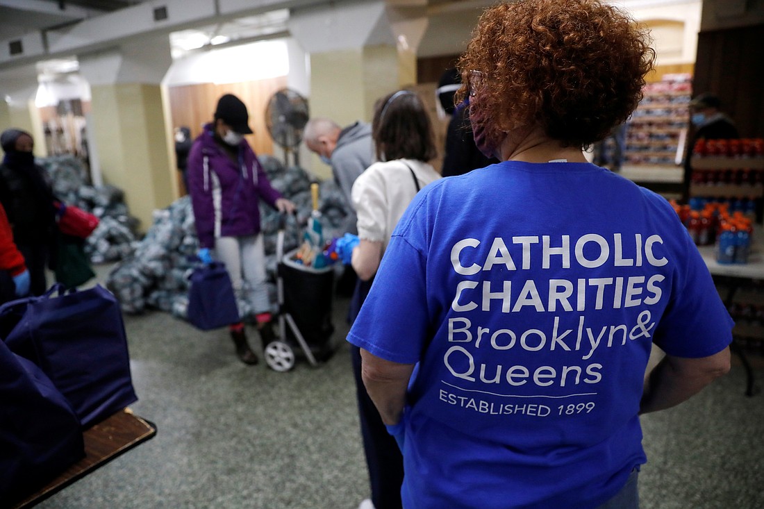 A volunteer in New York City looks on as people receive free food at a food pantry for needy residents run by Catholic Charities Brooklyn and Queens April 24, 2020. The Supreme Court ruled June 16, 2025, in favor of religious employers opposed to New York's requirement that their health insurance cover medically necessary abortions. (OSV News photo/Mike Segar, Reuters)